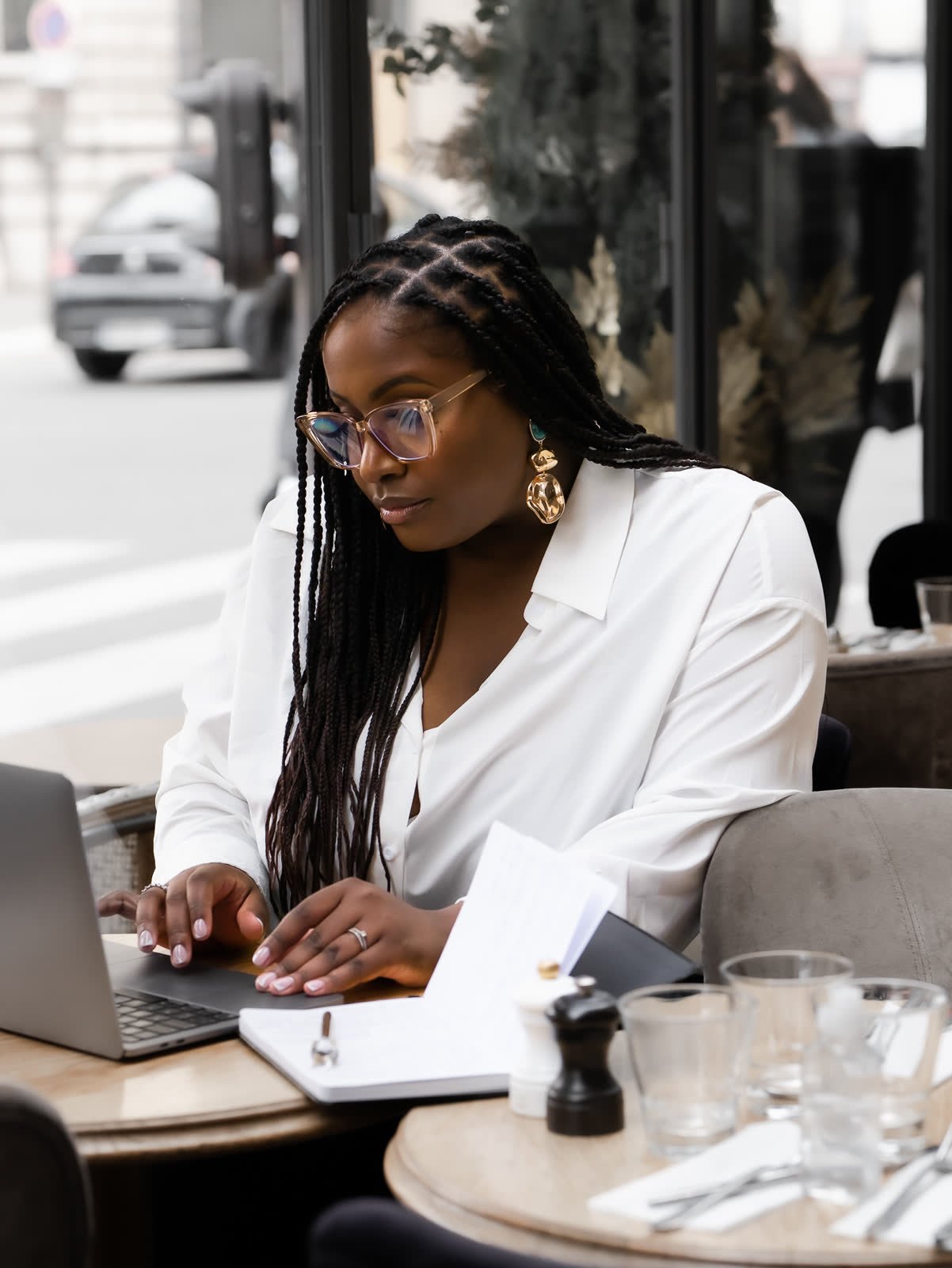 Amandine prend des notes à la terrasse d'un café, ordinateur ouvert