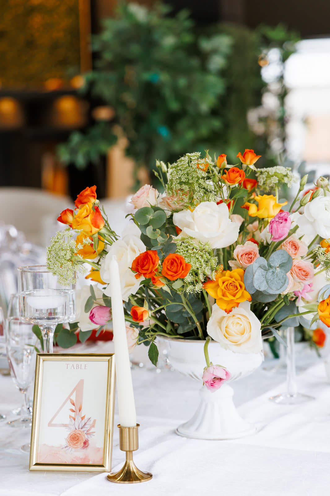 Centre de table de fleurs orange et blanches, bougie et cadre doré