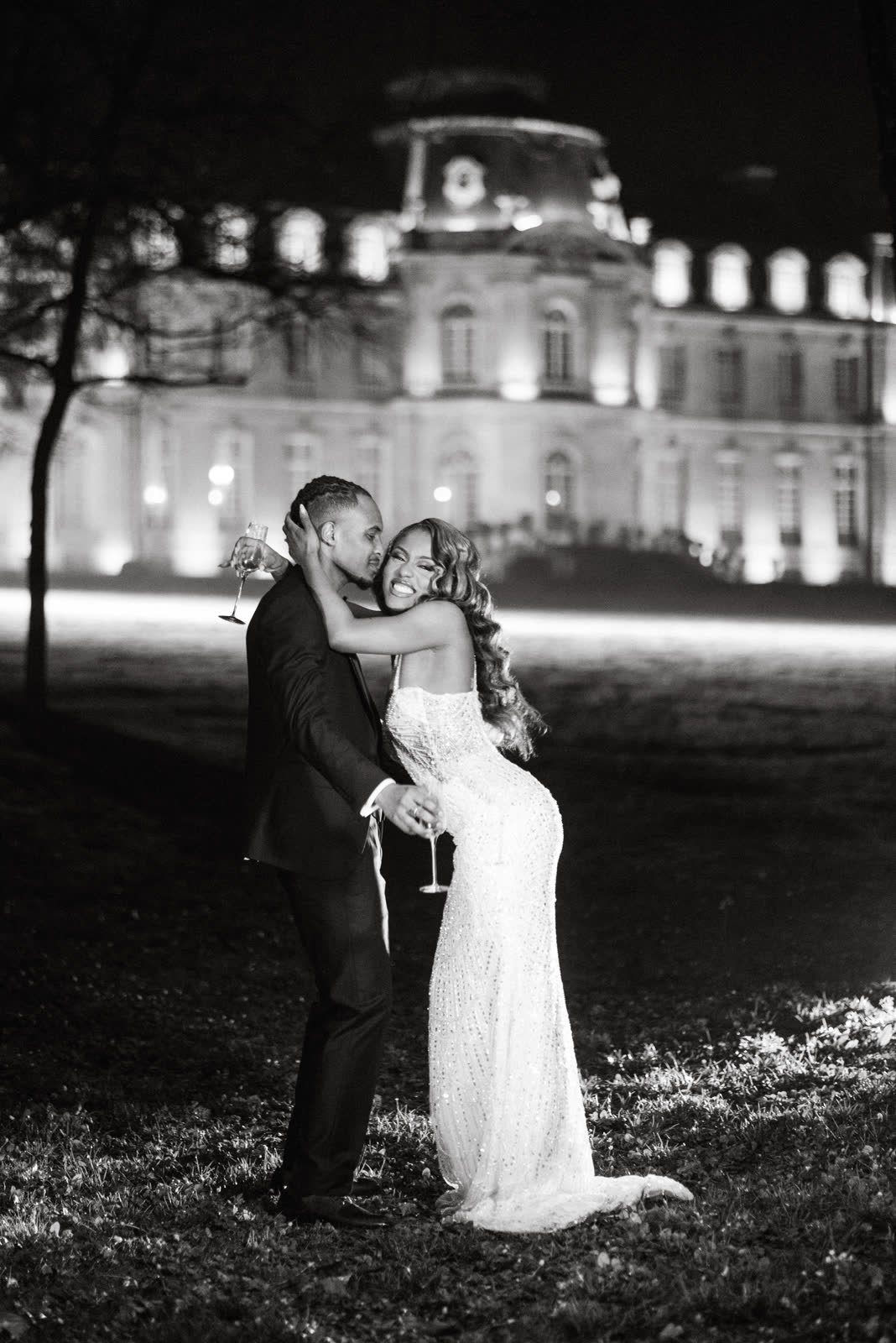 Les mariés devant un château illuminé, en noir et blanc